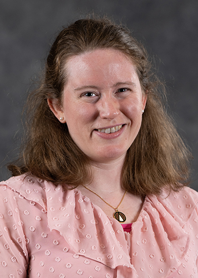 woman with long reddish-brown hair wearing a pink blouse