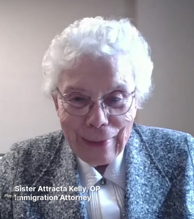 woman with white hair wearing glasses, a white collared blouse and a gray blazer